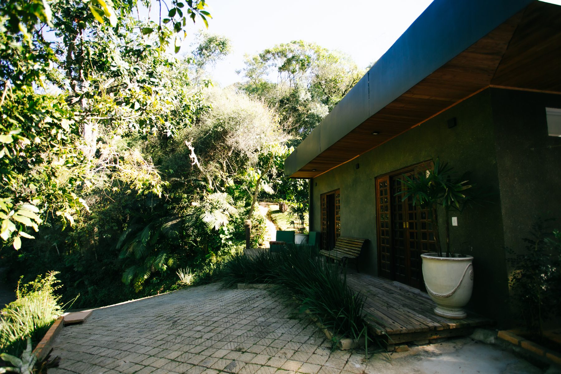 Fachada da Casa Vista com deck de madeira e mata ao redor