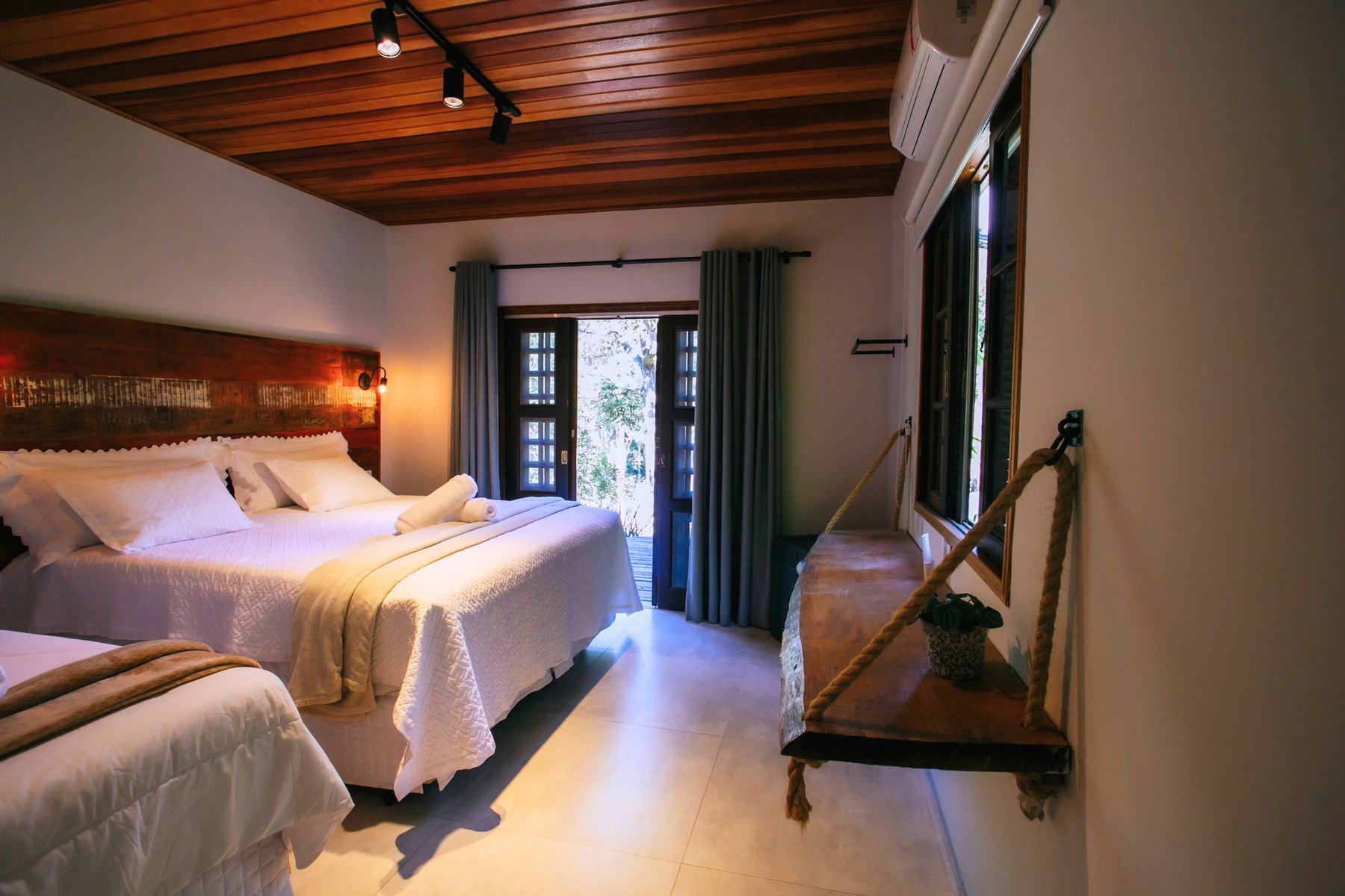 Quarto triplo da Casa Vista com porta de vidro voltada para o lago