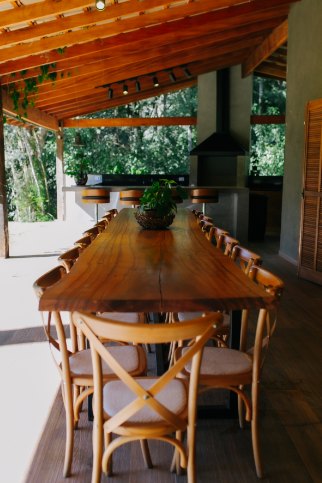 Mesa de madeira maciça com cadeiras de palha na varanda da Casa Lago