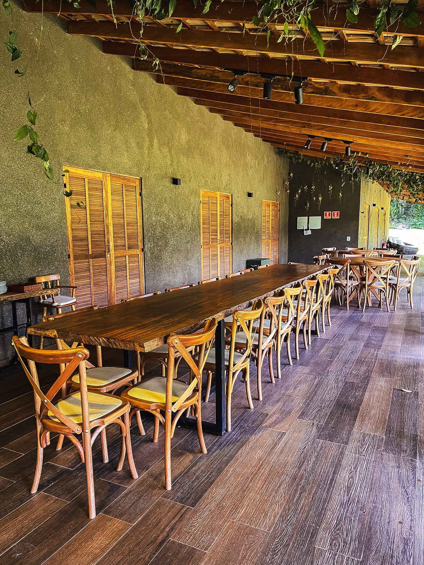 Varanda gourmet da Casa Lago com mesa comunitária de madeira e cadeiras de palha